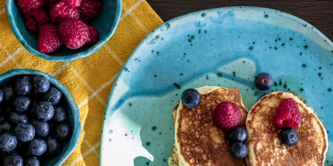 a plate of pancakes and bowls of berries
